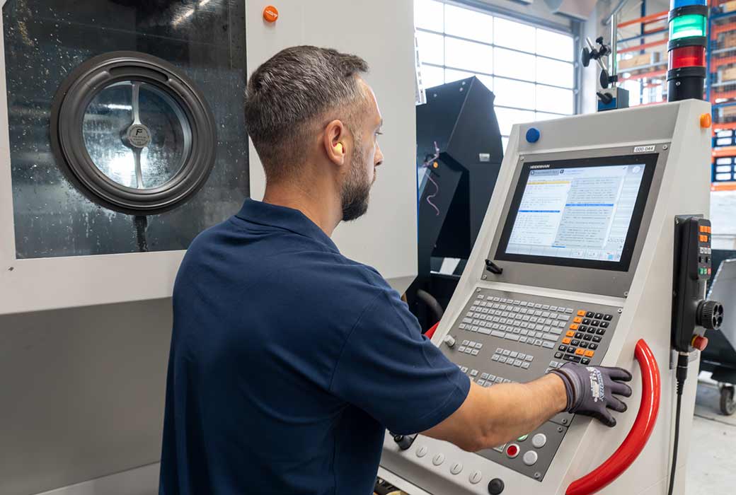 CNC-Maschinenbediener steuert ein Bearbeitungszentrum in der industriellen Fertigung