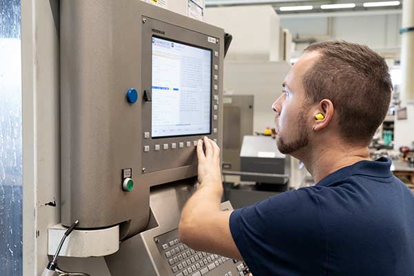 CNC machine operator working at the control panel of a machining center